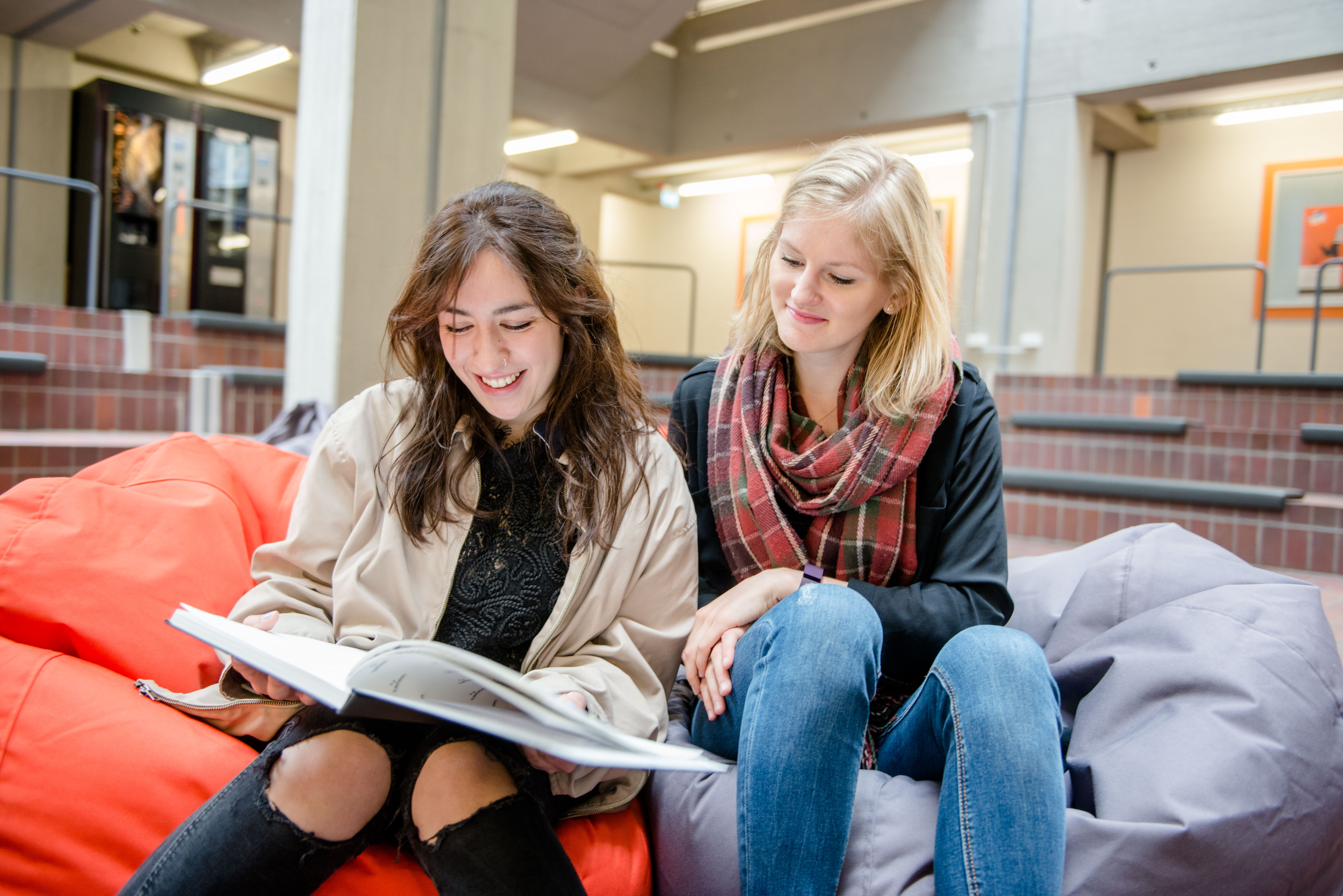 Zwei Studierende mit Buch im Universitätsforum Ost
