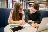 Zwei Studierende mit Laptop und Lernunterlagen