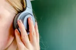 Frau im Profil mit Kopfhörer am Ohr.