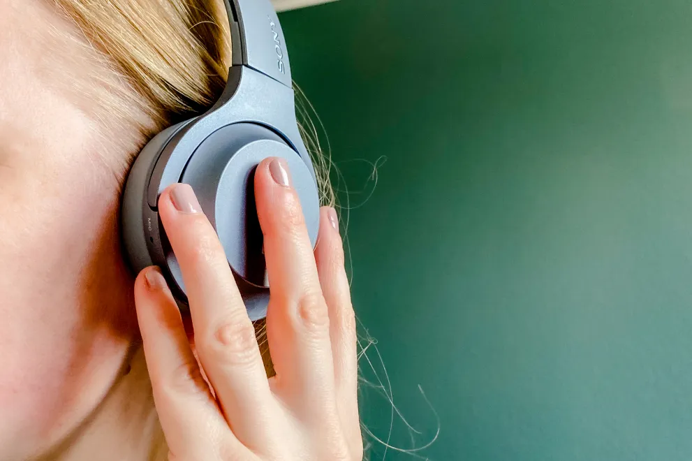 Frau im Profil mit Kopfhörer am Ohr.